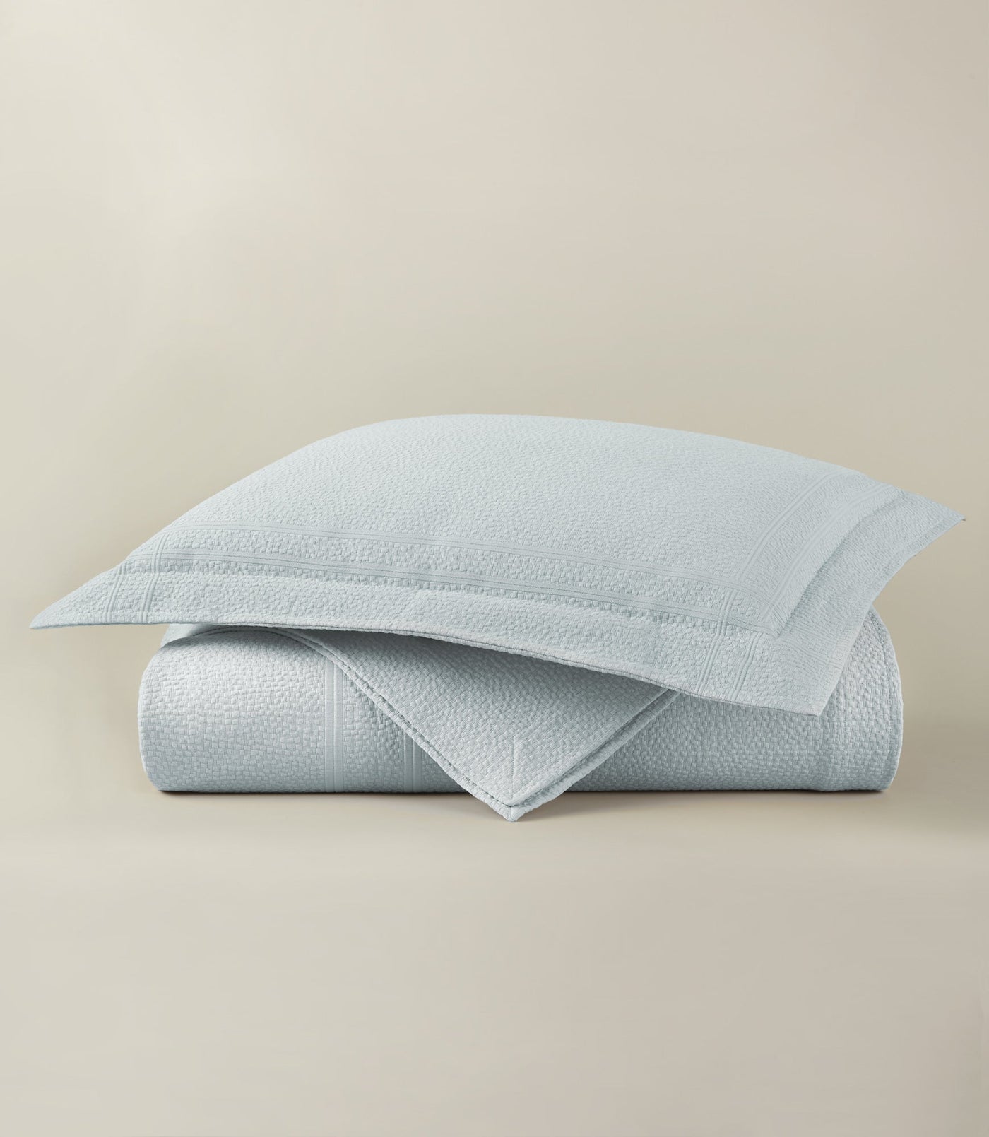 Close-up of folded powder blue Peacock Alley Montauk coverlet with matching sham, textured weave detail.