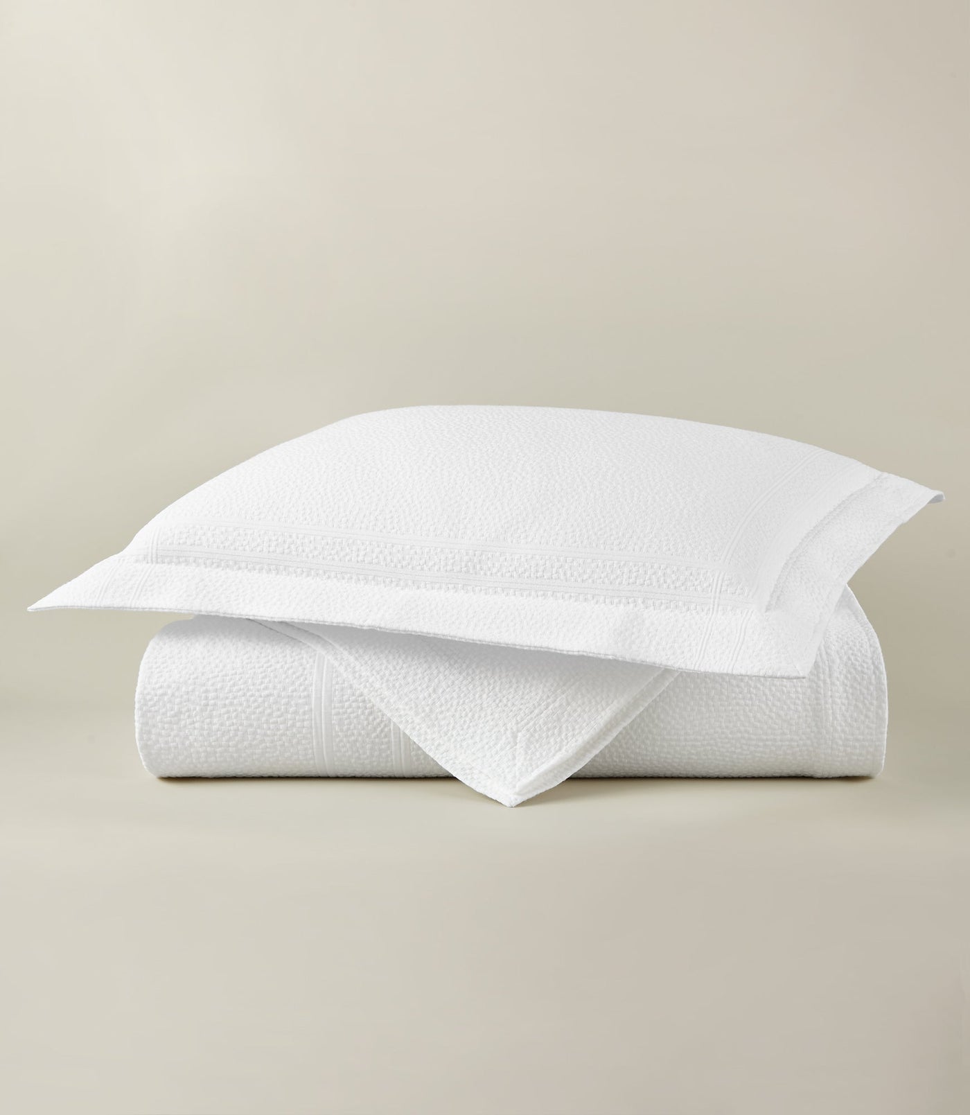 Close-up of folded white Montauk coverlet with textured matelassé weave and matching sham.