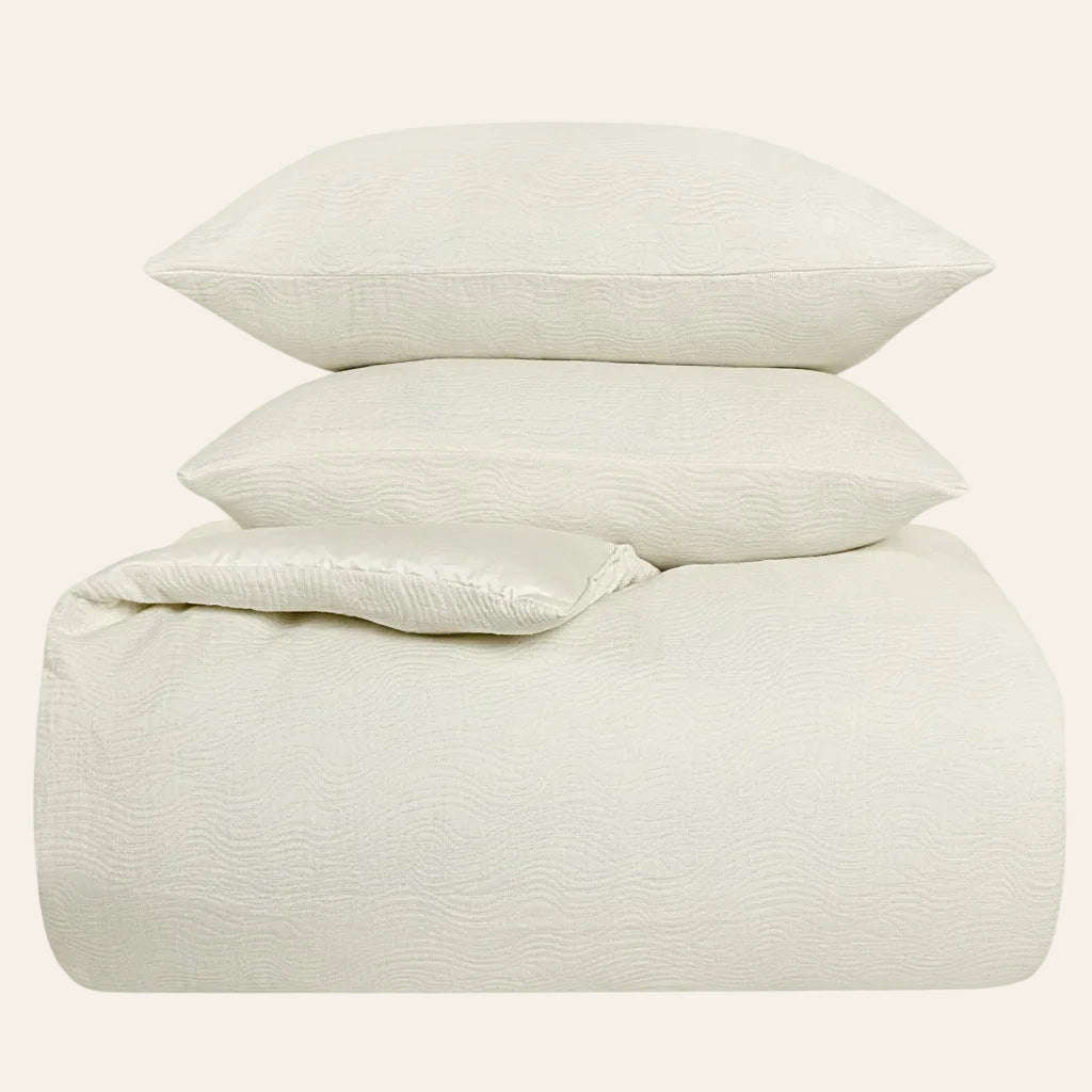 Ann Gish Moonstone ivory comforter set with two pillows, textured wave pattern.