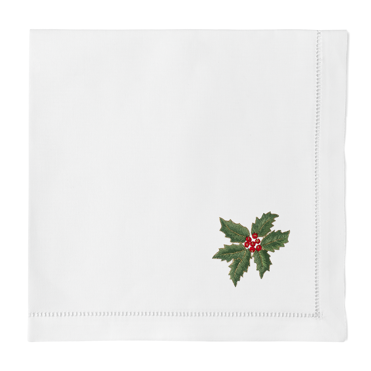 Close-up of embroidered holly and red berries on white linen napkin corner with hemstitch border.