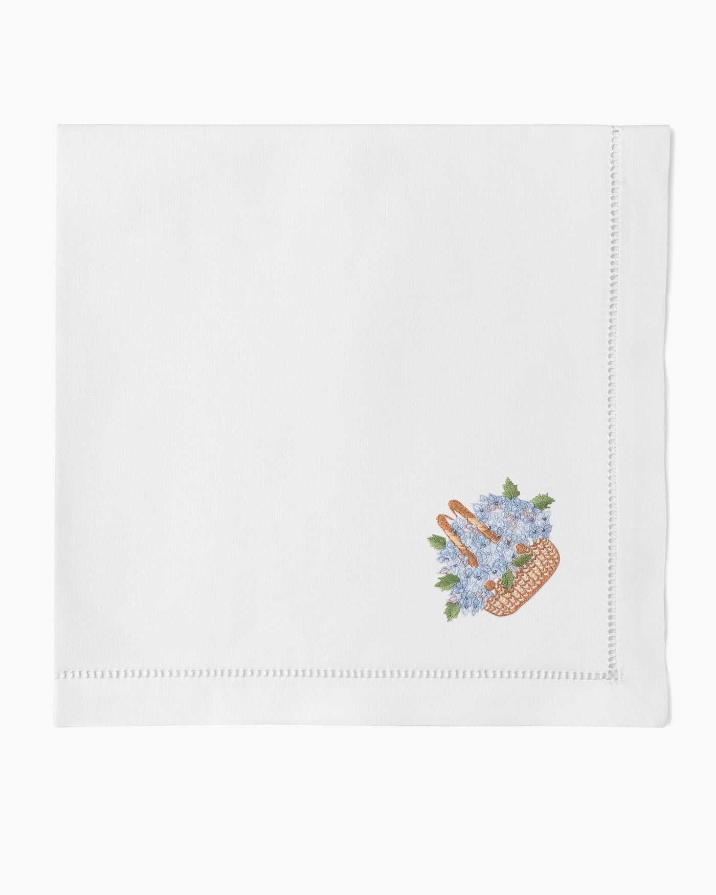 Henry Handwork white linen dinner napkin with embroidered Nantucket basket and blue flowers.