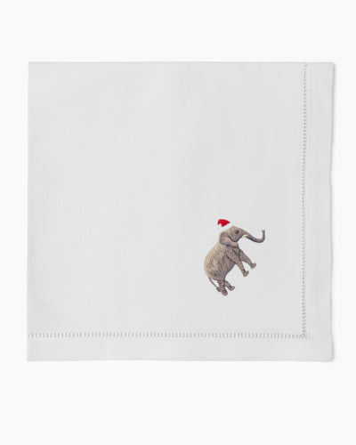 Henry Handwork white linen napkin with embroidered elephant in Santa hat, hemstitch border.
