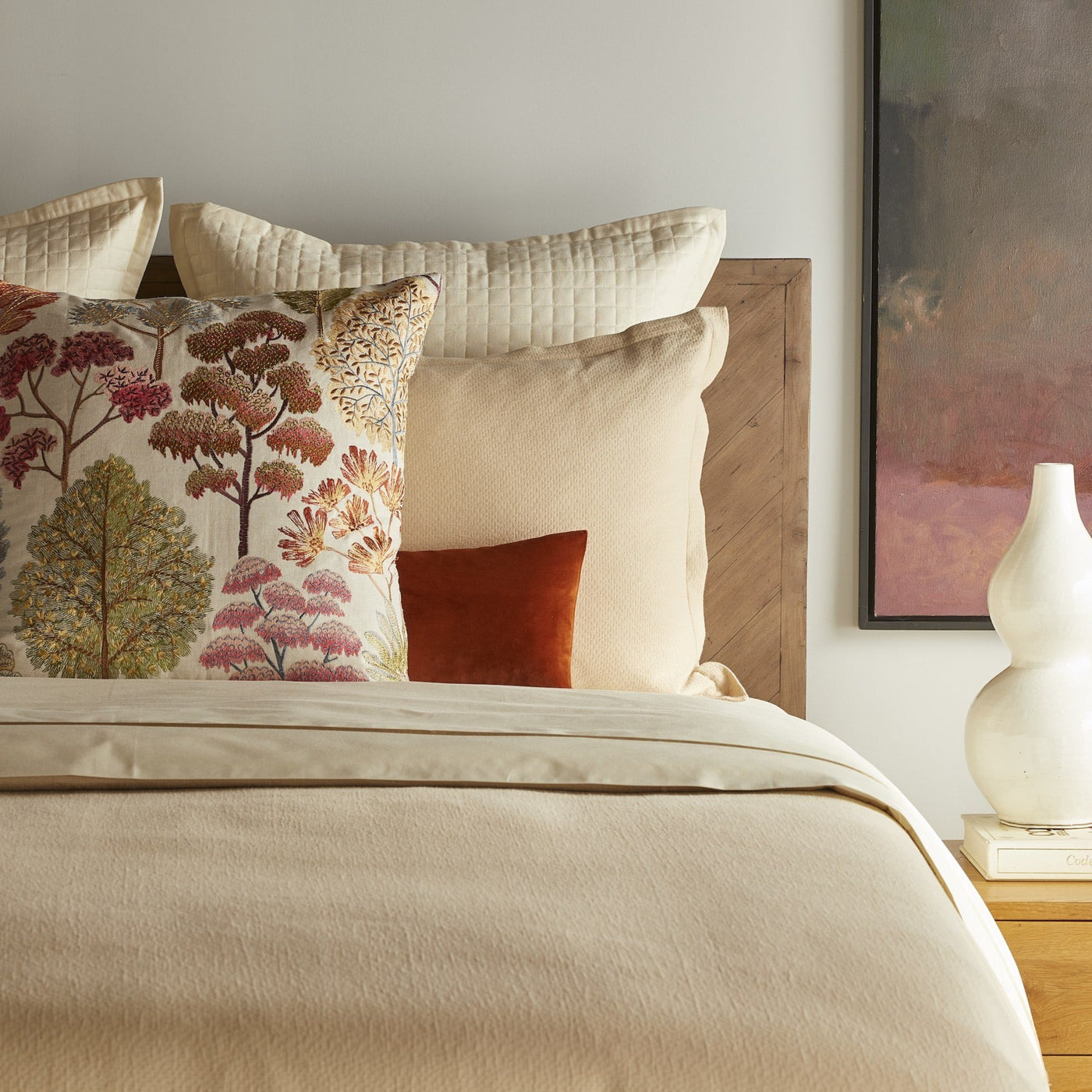 Ivory textured duvet set styled with floral and rust accent pillows on a wood headboard bed.