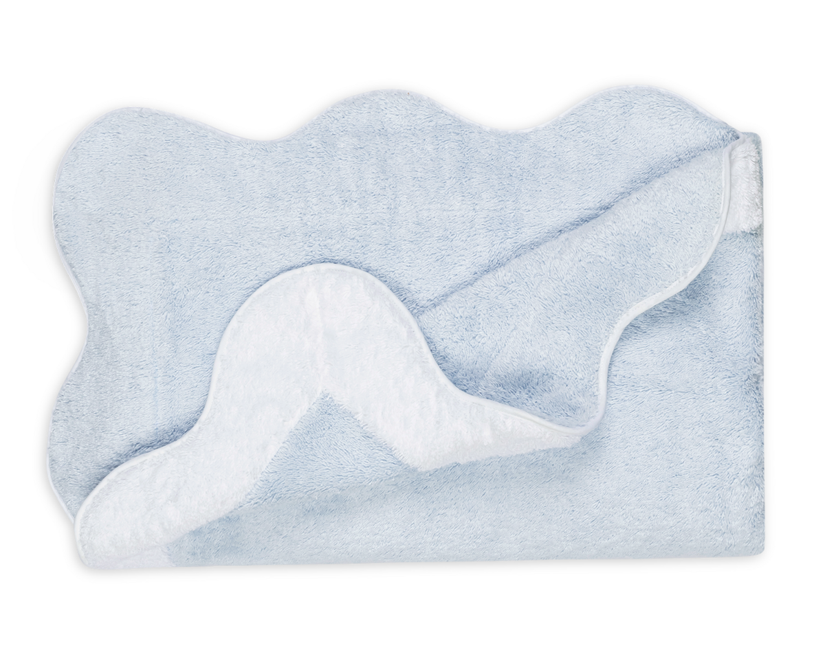 The Neptune Pool Towel by Matouk is a light blue, rectangular Cairo cotton towel with scalloped edges, shown partially folded to reveal the white underside against a plain background.
