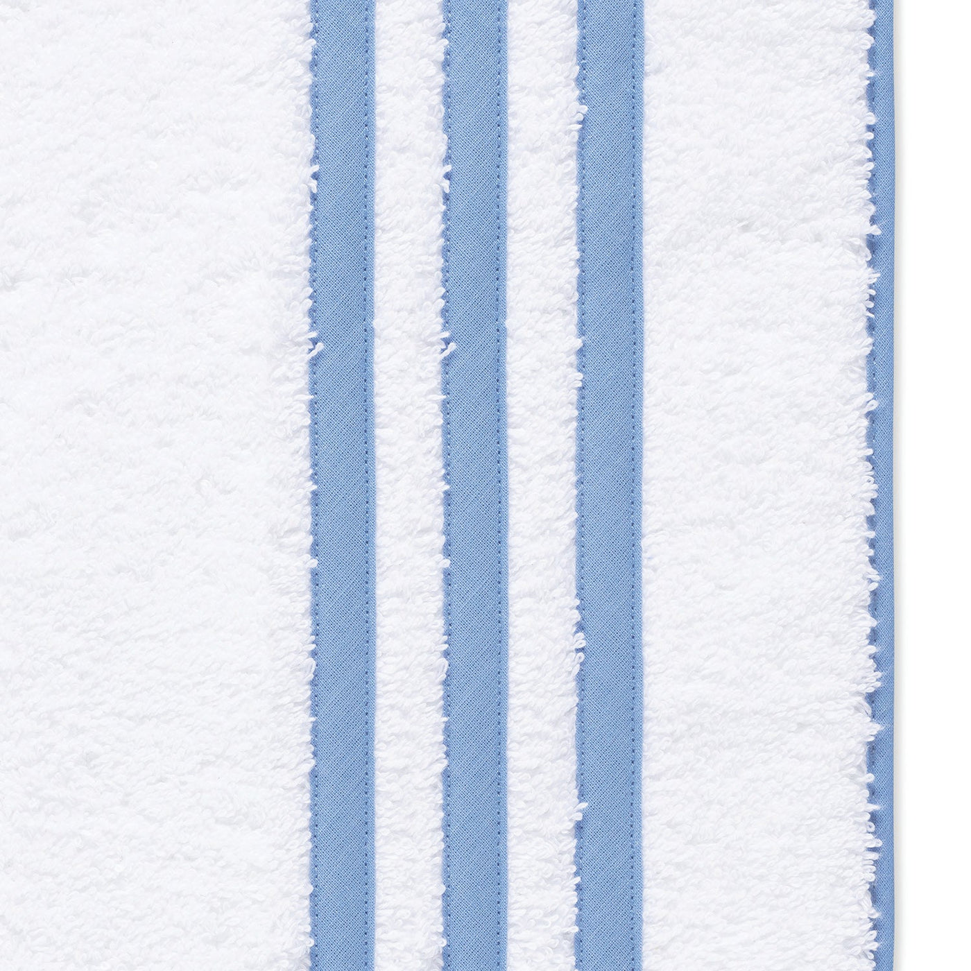 Close-up of the Matouk Newport Shower Curtain, featuring white fabric with three vertical light blue stripes near the edge, inspired by diamond pique textures.