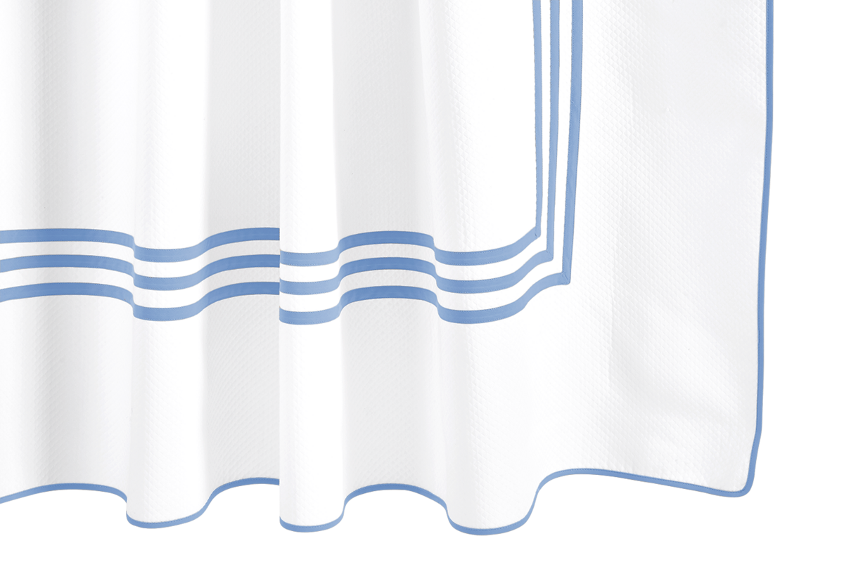 The Matouk Newport Shower Curtain features white diamond pique fabric with a blue triple stripe border, shown in soft folds—an elegant addition to your bath linens.