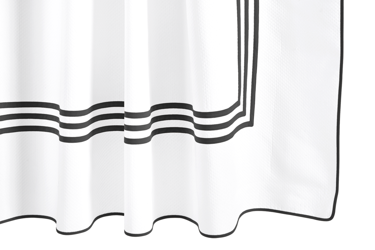 The Matouk Newport Shower Curtain features crisp white fabric with a black triple-stripe border, hanging in soft folds for an elegant touch to your bath linens.