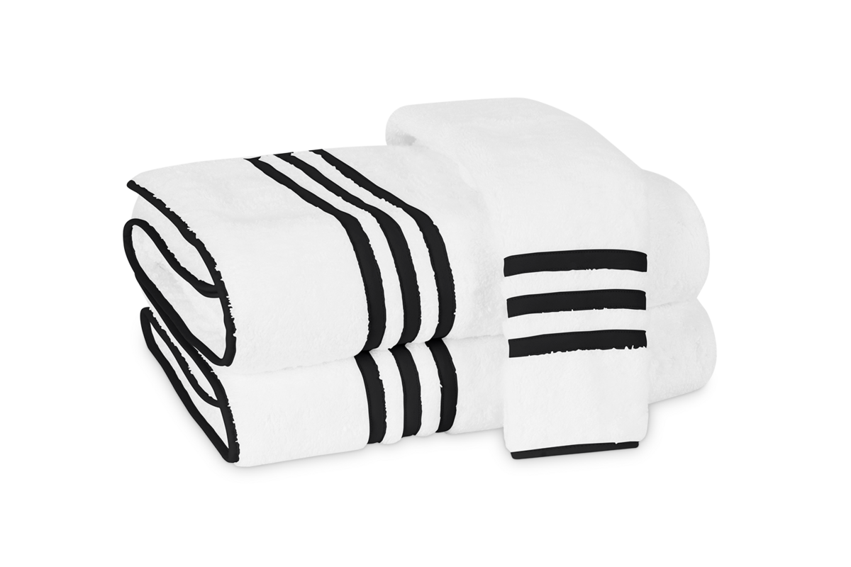 Three folded Newport bath towels by Matouk, featuring white fabric with black stripes and an appliqué-tape border, are displayed on a plain background.