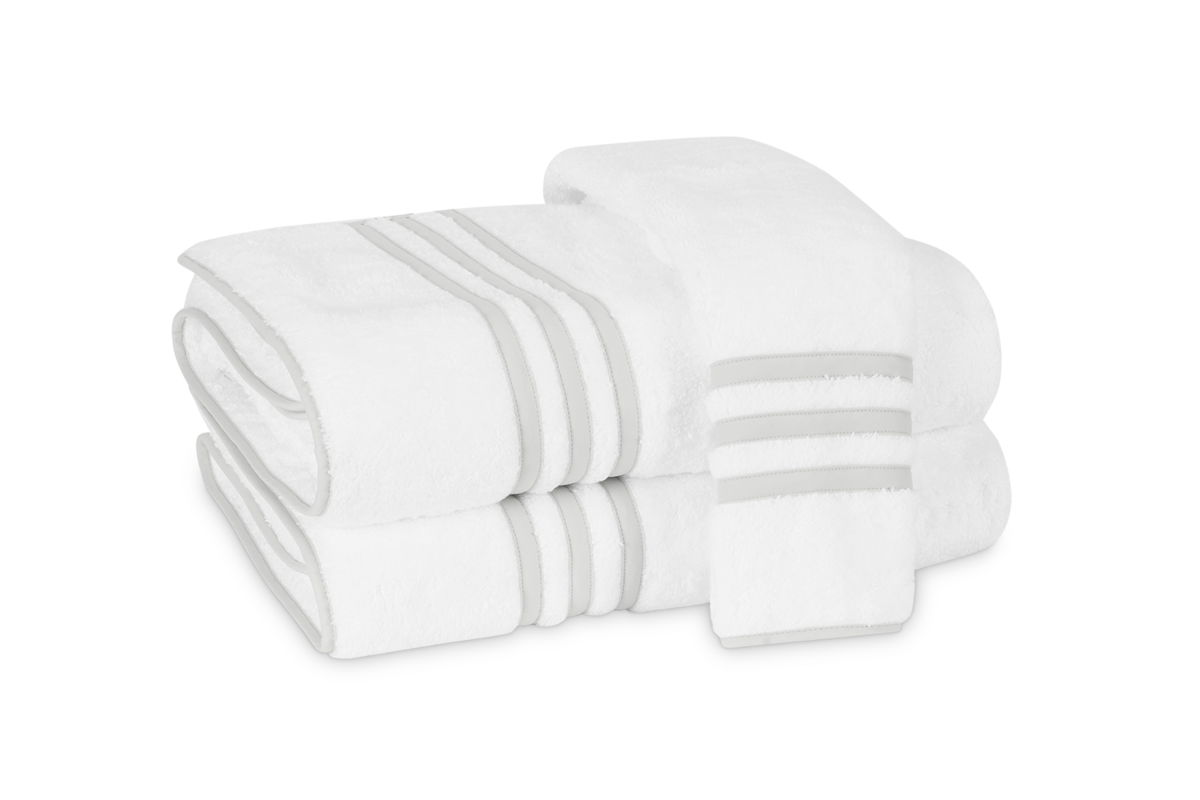 Three folded Newport Bath Towels by Matouk, featuring elegant light gray stripes and crafted from soft Cairo cotton terry, are stacked on a light background.