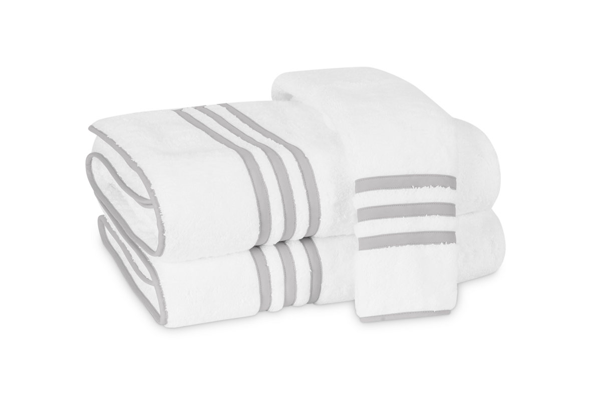 A stack of three Newport | Bath Towels by Matouk, crafted from Cairo cotton terry, featuring light gray stripes and trim, neatly folded on a plain background.