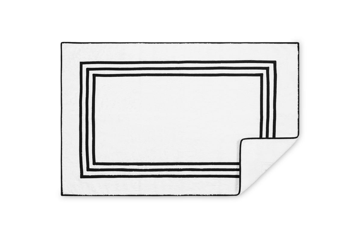 Corner detail of Matouk Newport tub mat showing triple black border frame on white.