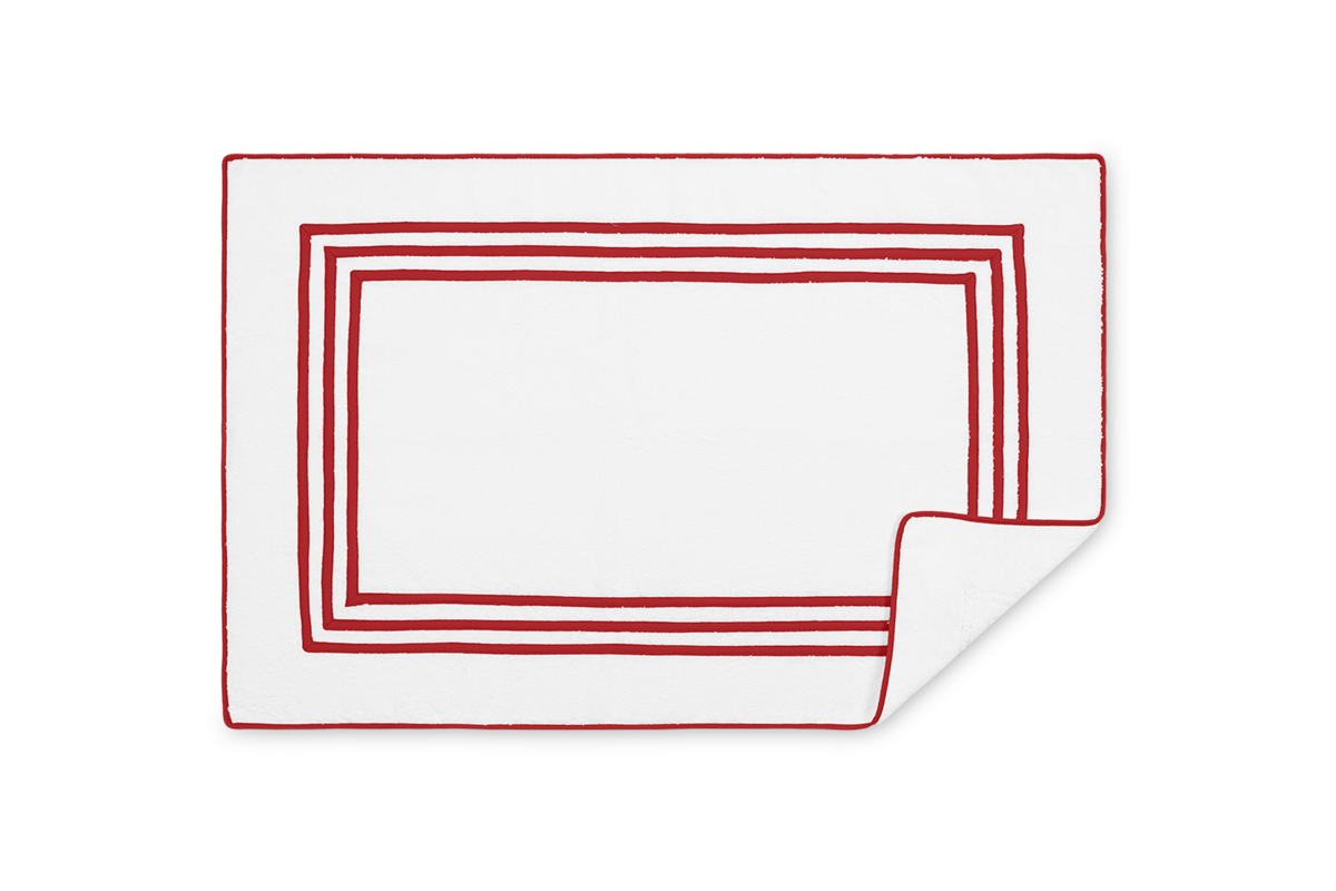 Close-up of white tub mat with red triple-stripe border, corner folded to reveal reverse side.