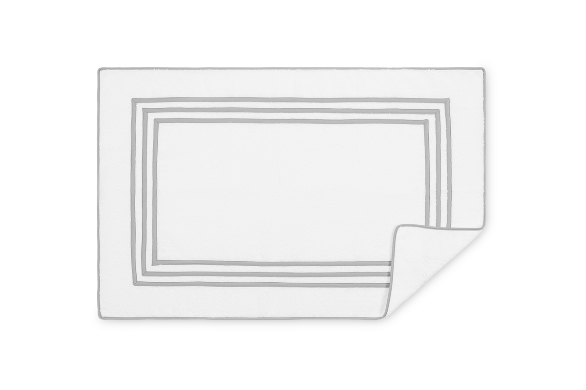 Corner fold detail on white Matouk Newport tub mat with silver triple-stripe border.