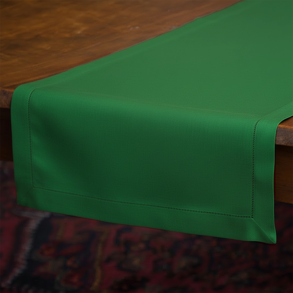 Emerald green linen table runner with hemstitch border draped over a wooden table.