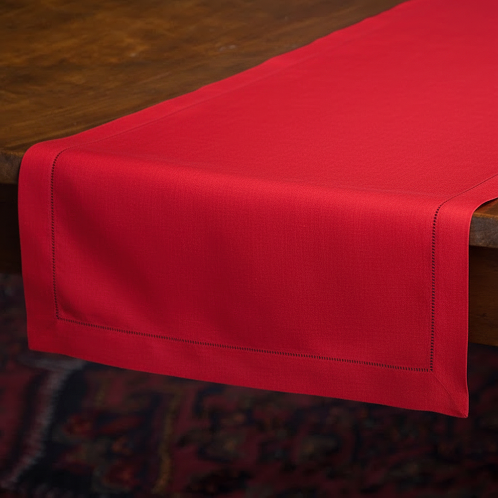 Henry Handwork Noël crimson linen table runner with hemstitch border on wood table.