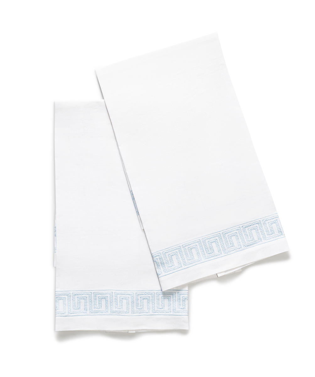 The Ophelia Embroidered Guest Towel Set by Matouk features two luxury towels with a light blue Greek key pattern along the edges, displayed overlapping on a plain white surface.