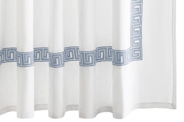 The Ophelia Shower Curtain by Matouk features an embroidered horizontal blue Greek key pattern border near the bottom and along the side.