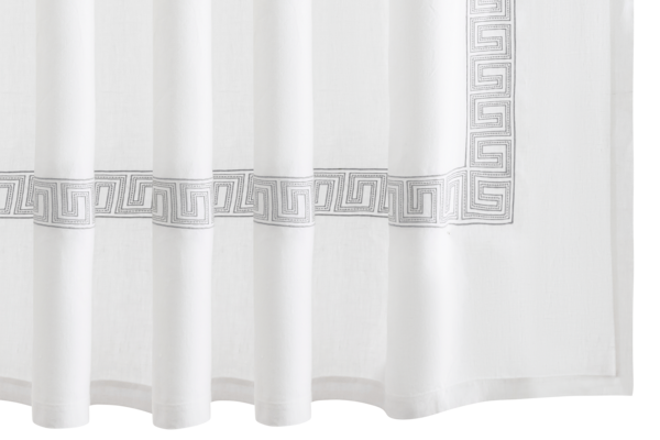 The Ophelia Shower Curtain by Matouk features white linen with an embroidered gray Greek key pattern near the bottom edge.