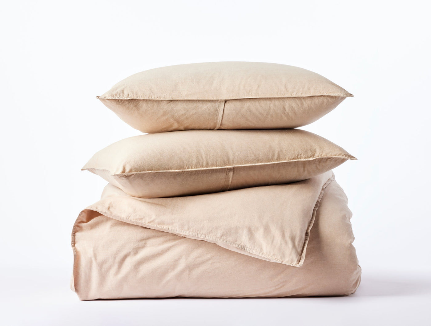 Two stacked sand-toned Coyuchi Crinkled Percale pillow shams atop a folded duvet cover.