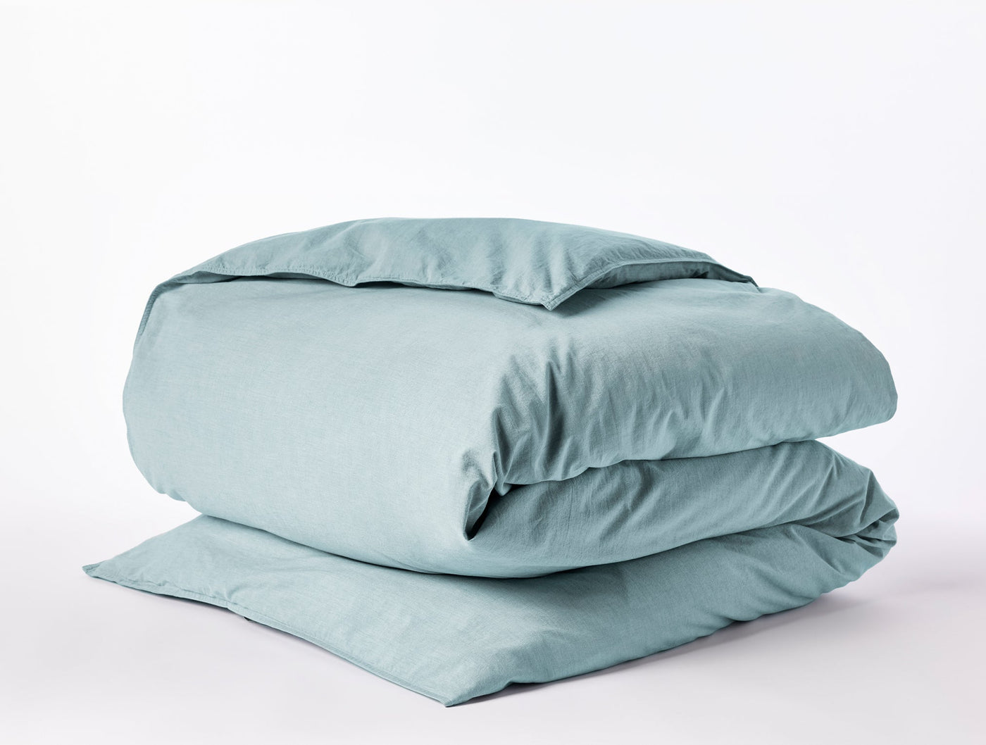 Coyuchi Crinkled Percale duvet cover folded, shown in muted aqua with relaxed texture.