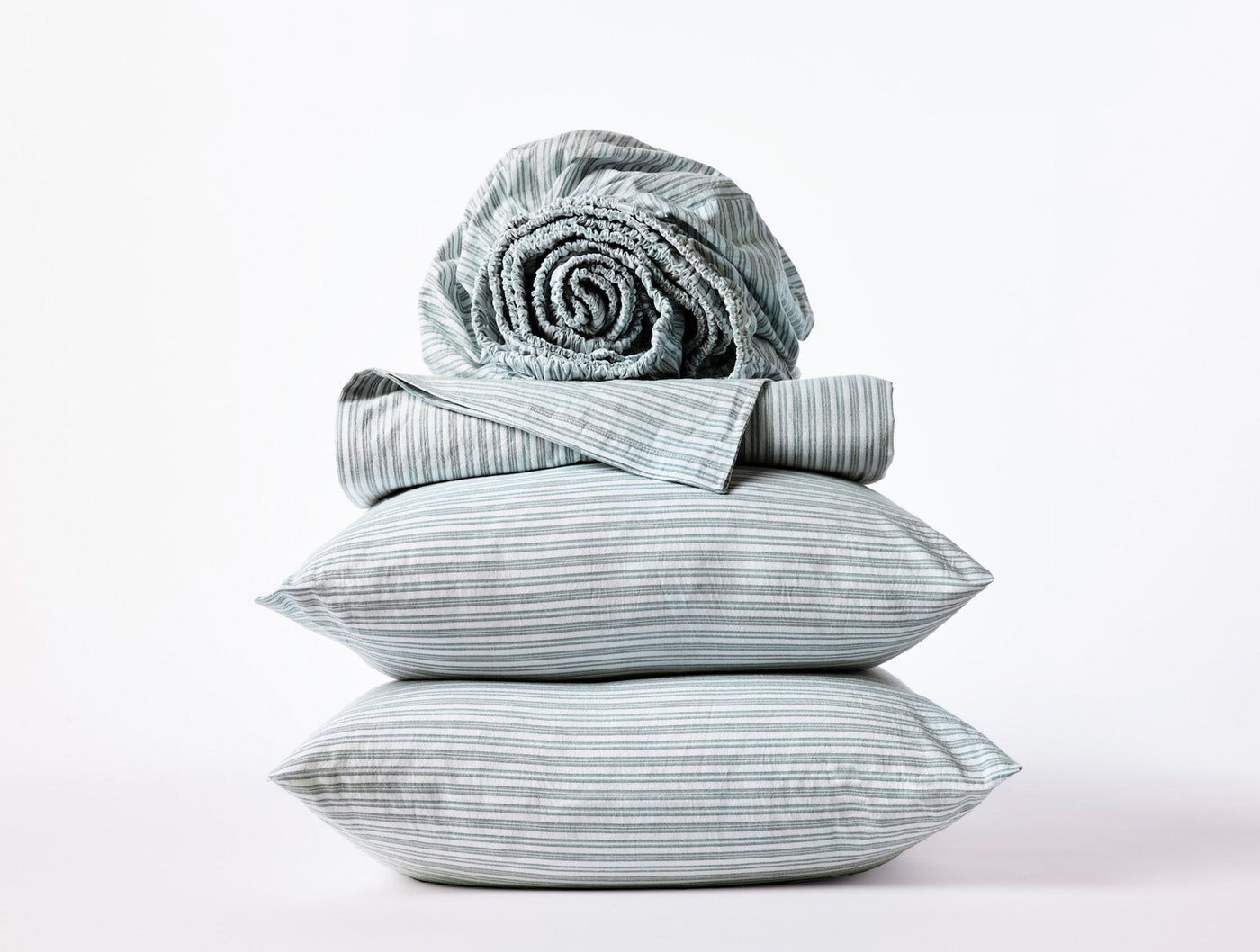 Coyuchi Crinkled Percale pillowcases stacked with striped sheet set in mist blue and white.