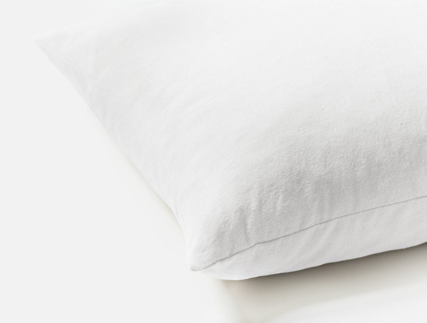 Close-up corner view of the Coyuchi Latex pillow in white, showing soft fabric texture.