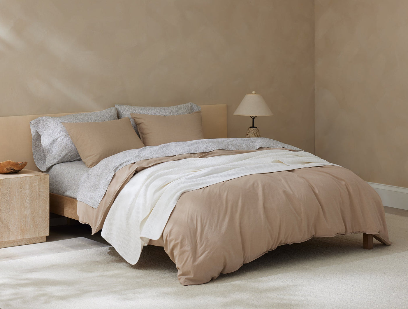 Close-up of a honeycomb-textured ivory blanket draped across a styled bed with camel bedding.