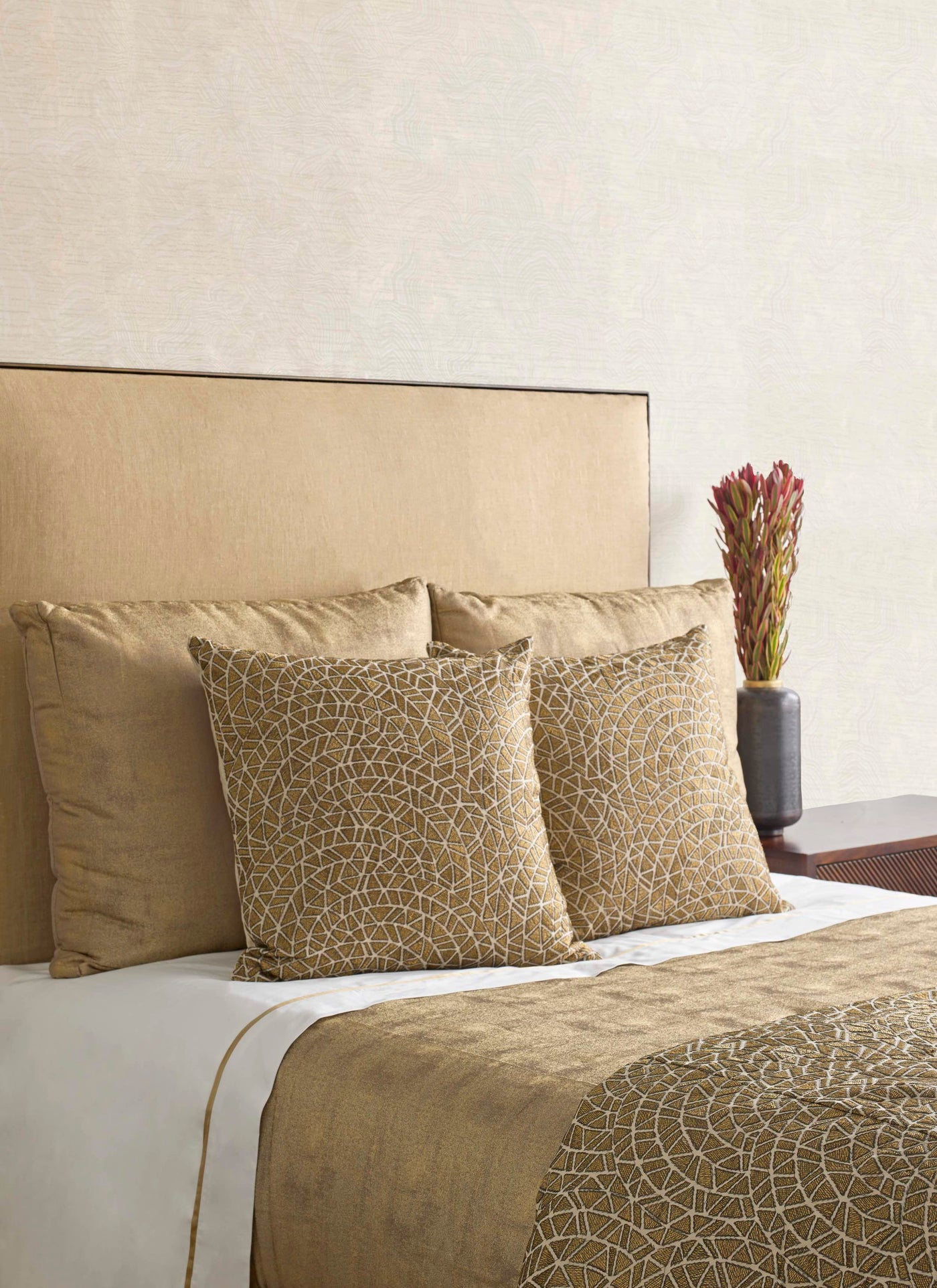 Styled bed showing Ann Gish Ornament duvet with gold geometric embroidery and coordinating pillows.