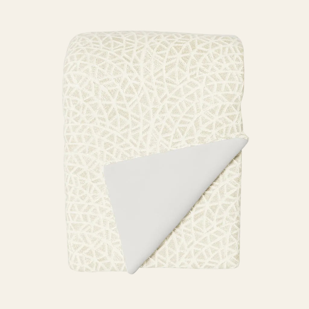 Ann Gish Ornament throw in ivory with geometric lattice pattern, corner folded to reveal plain reverse.