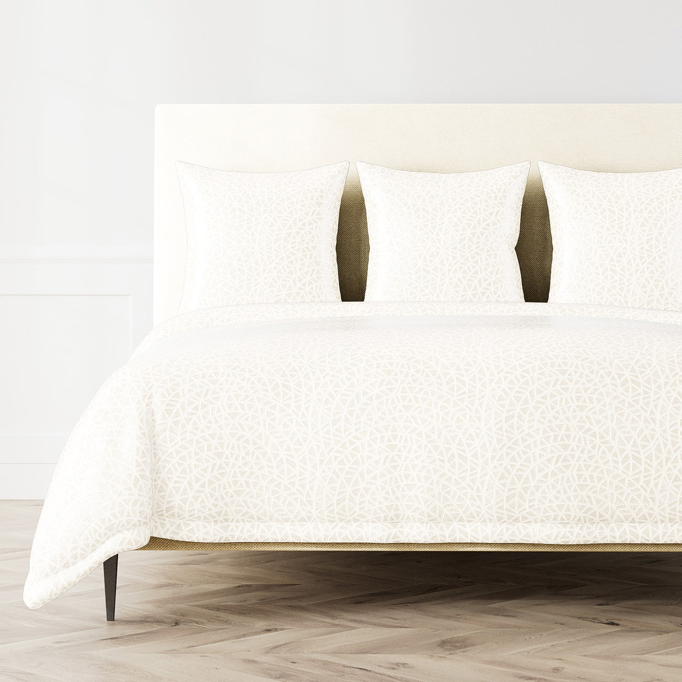 Ann Gish Ornament duvet cover in ivory with tonal floral pattern, styled on a bed with matching shams.