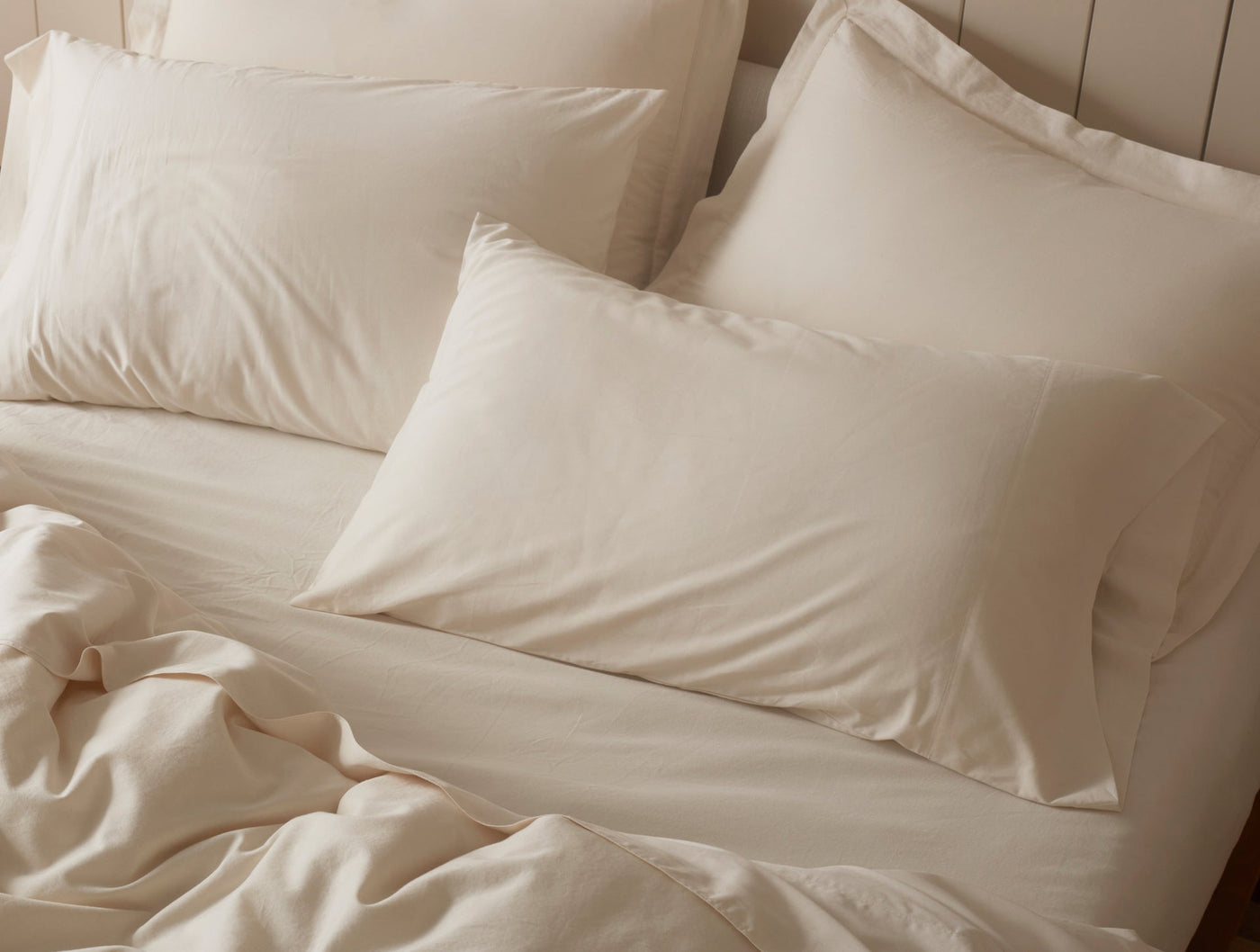 Ivory sateen duvet cover and pillowcases styled on a bed, softly rumpled.