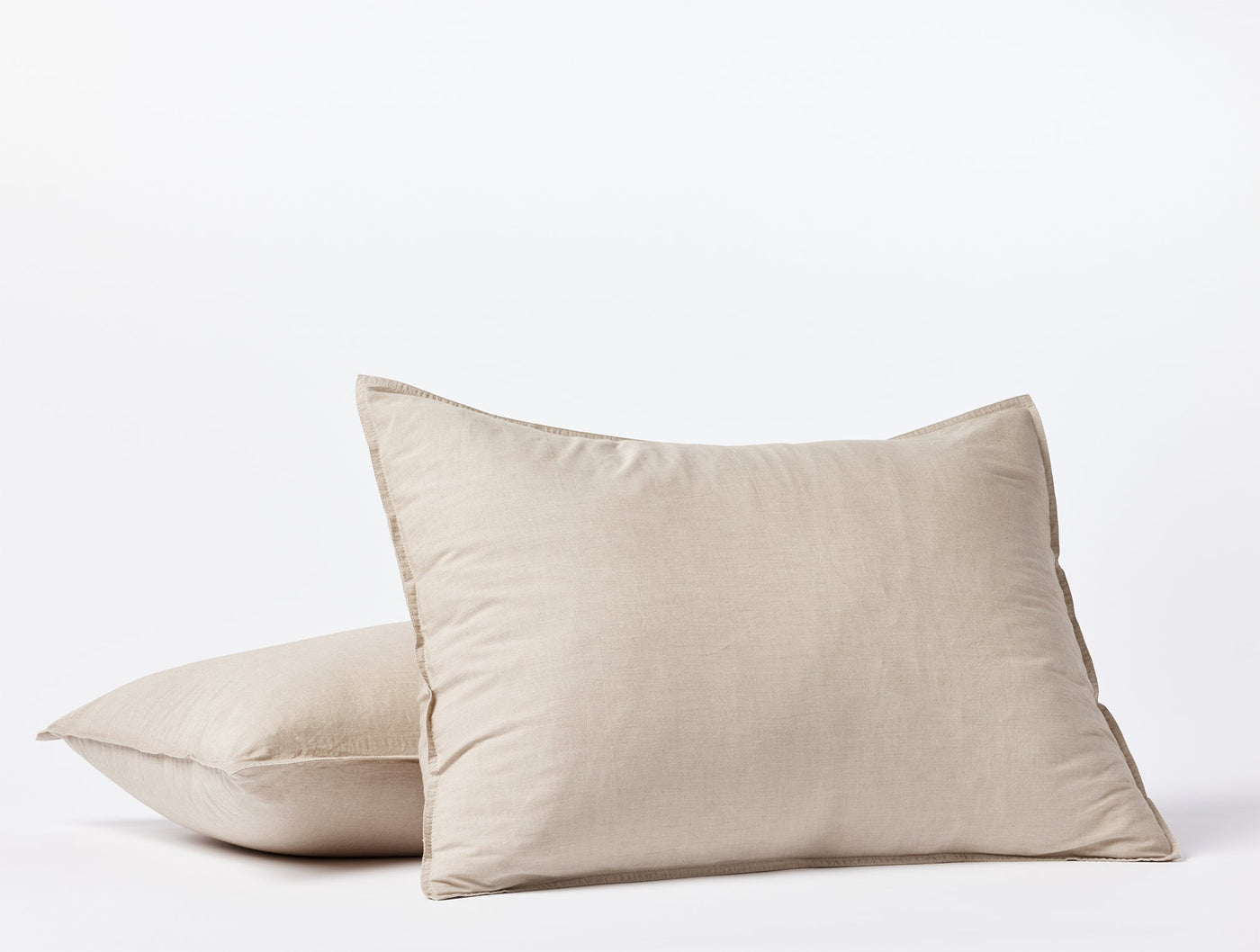 Close-up of two stacked Coyuchi Crinkled Percale pillow shams in natural linen tone.