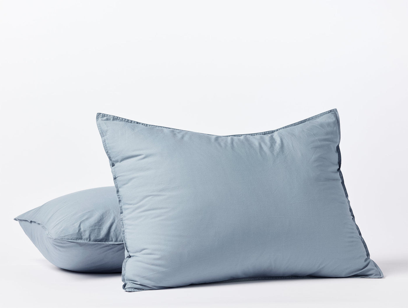 Two slate blue Coyuchi Crinkled Percale shams stacked, showing relaxed texture and flange edge.