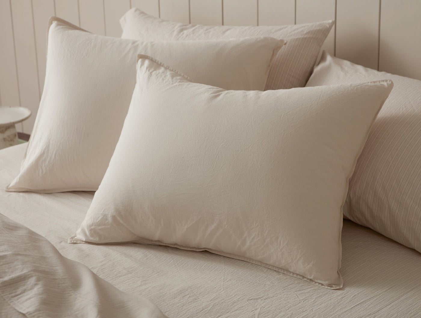 Pair of sand Coyuchi Crinkled Percale shams stacked on a made bed.
