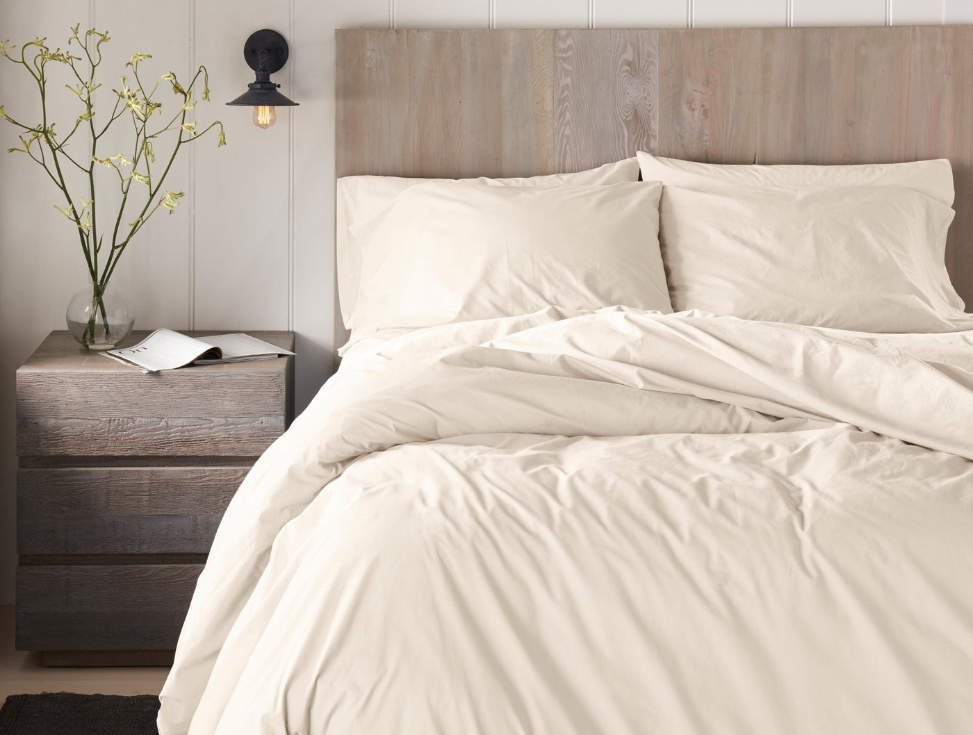 Ivory percale flat sheet draped loosely over a styled bed with matching pillowcases.