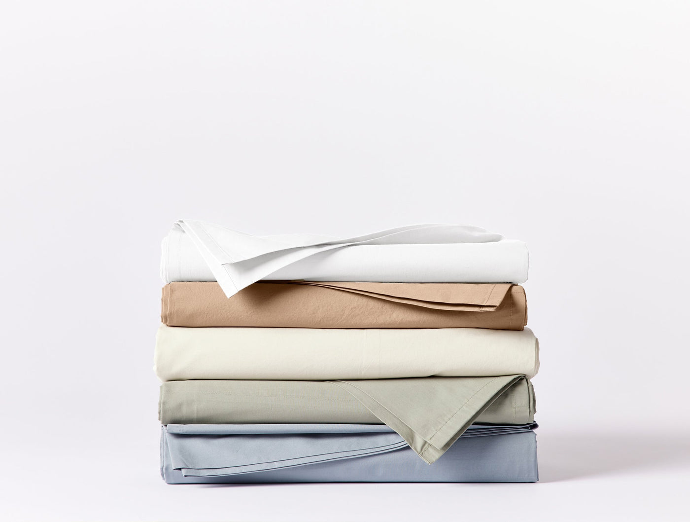 Stack of four folded Coyuchi Refined Percale sheet sets in white, camel, sage, and slate blue.
