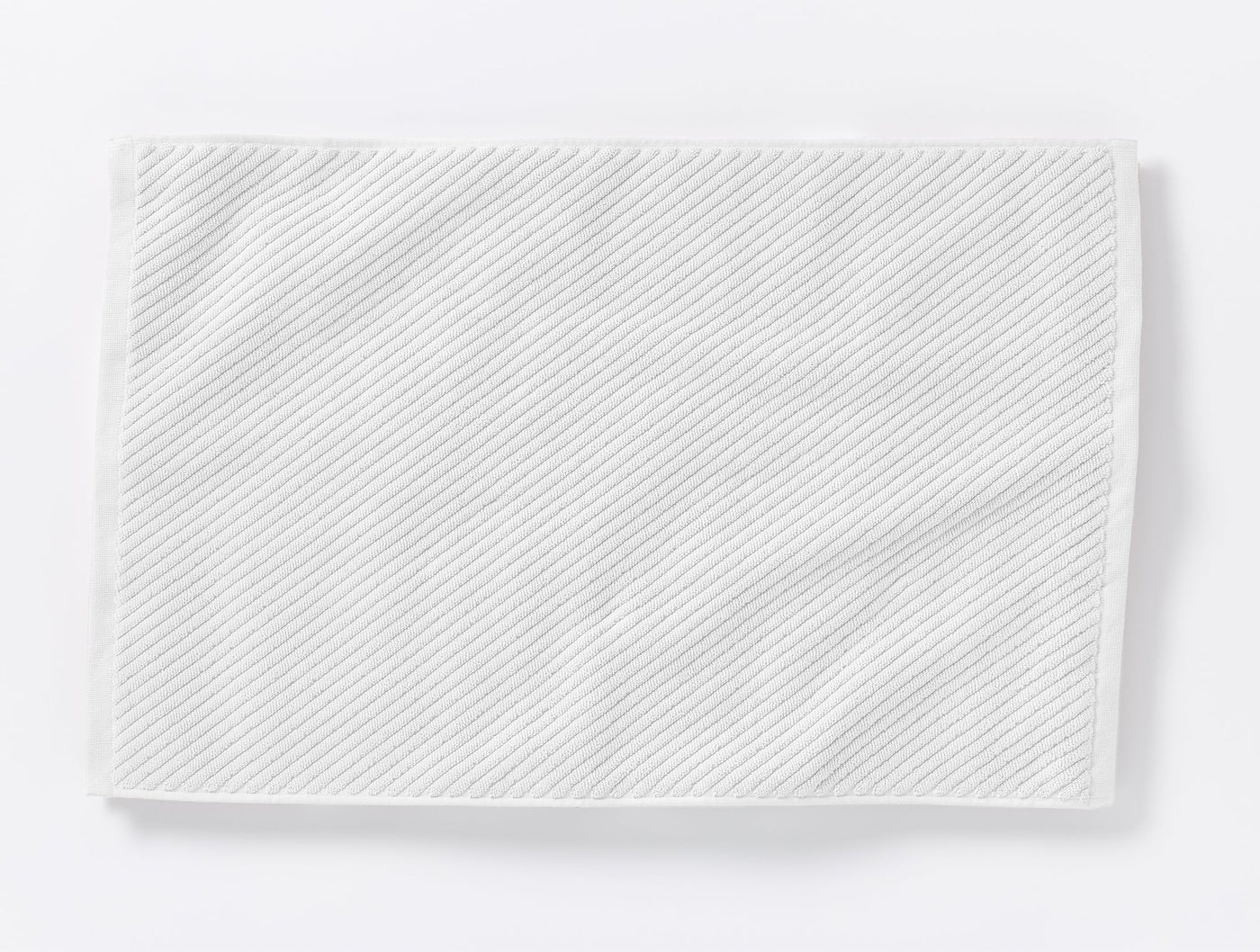 Coyuchi Air Weight white twill bath rug with diagonal ribbed texture.