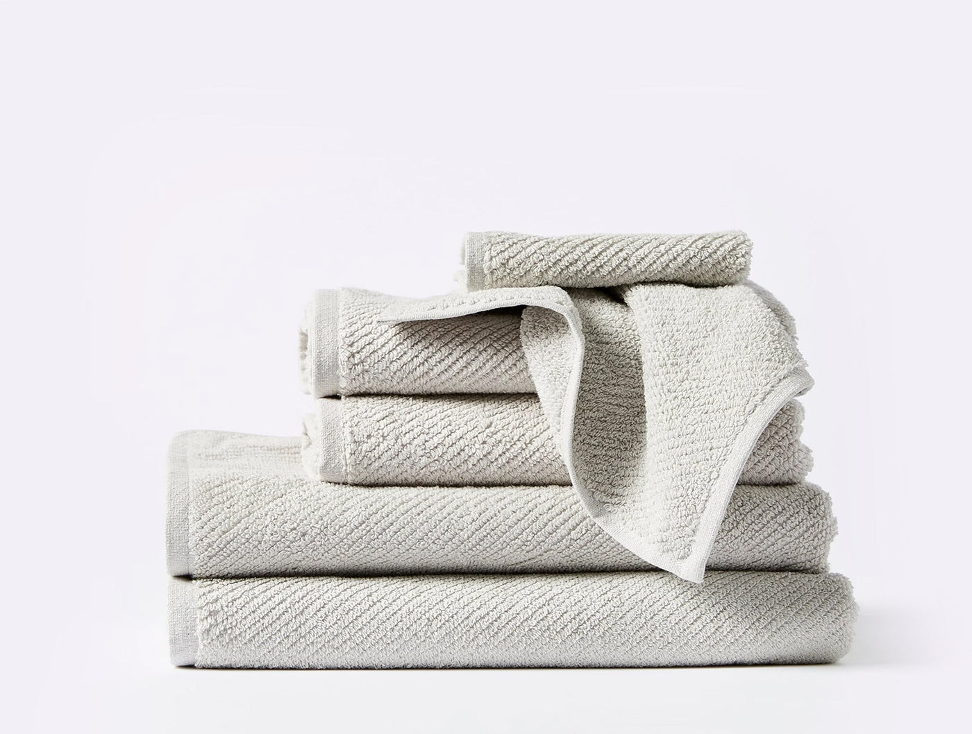 Stacked Coyuchi Air Weight towel set in silver, showing diagonal ribbed texture.