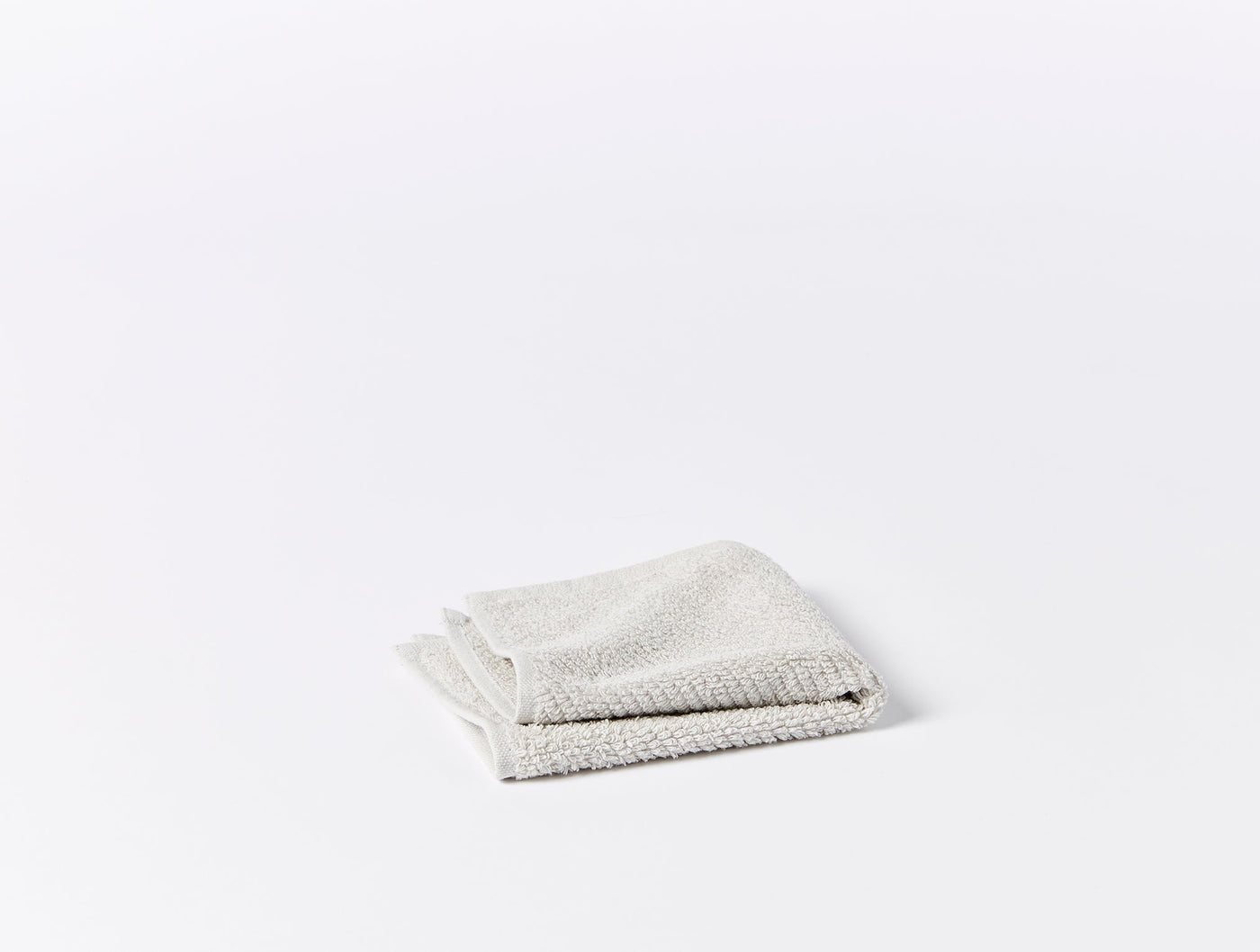 Close-up of folded ivory Coyuchi Air Weight washcloth showing textured waffle weave.