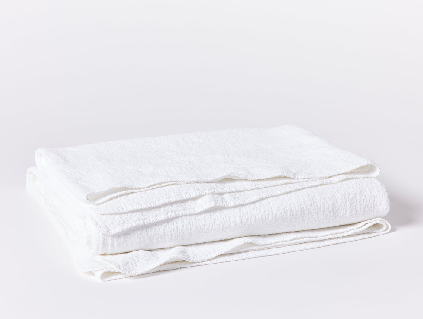 Coyuchi Cascade Matelasse blanket in white, neatly folded showing textured weave.