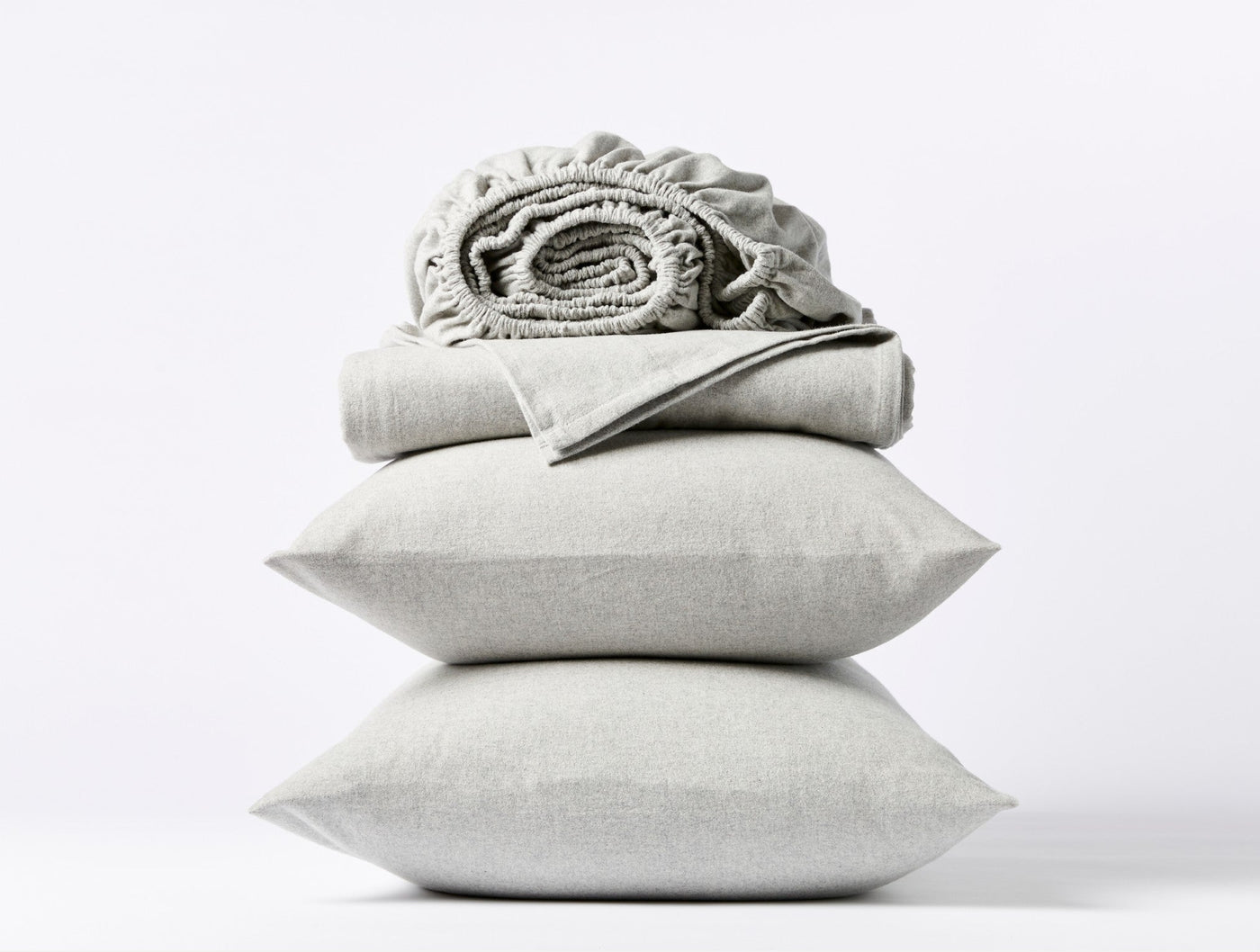 Sage green flannel fitted sheet rolled atop two stacked matching pillowcases.