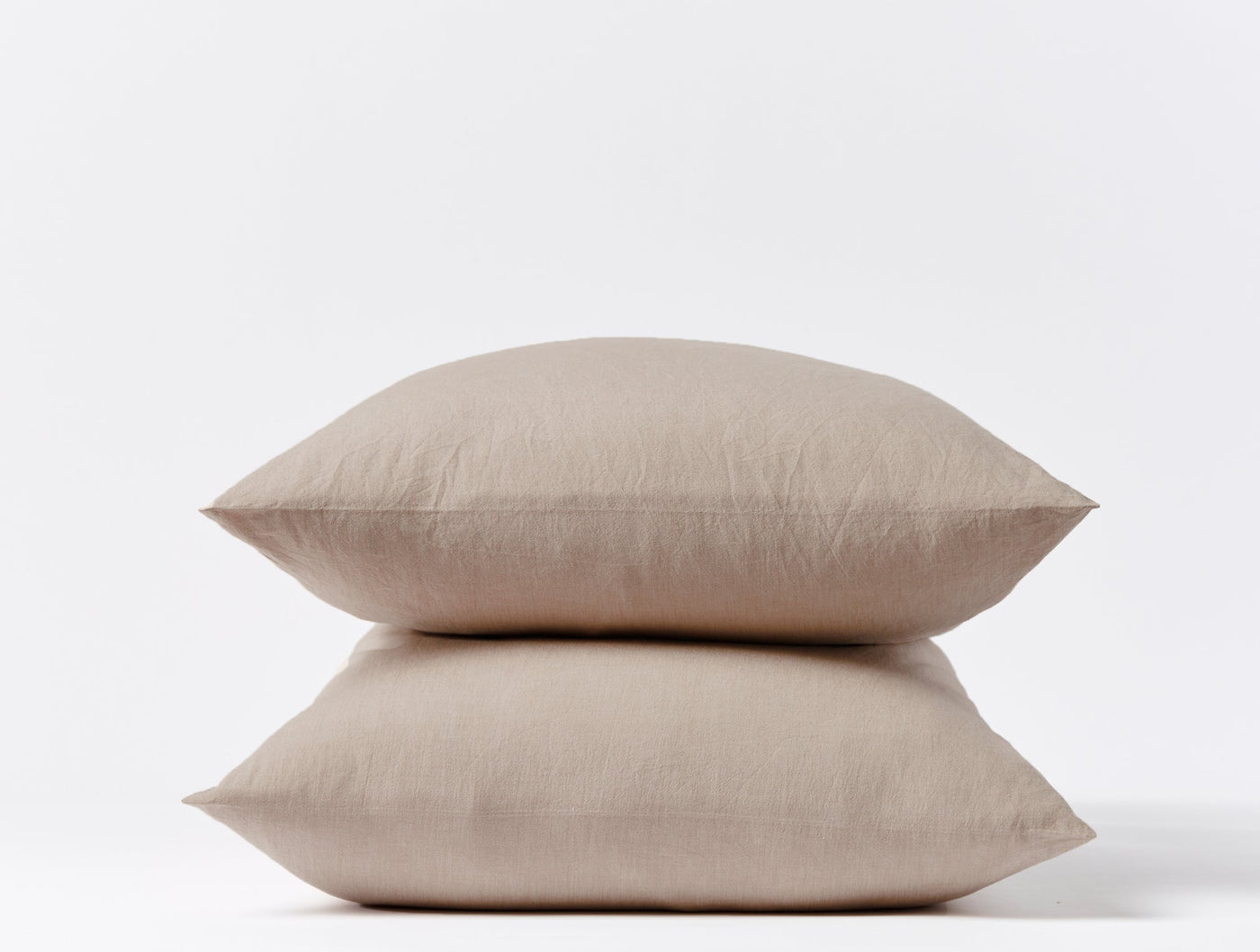 Two stacked dune Coyuchi Crinkled Percale pillowcases showing relaxed texture on white background.