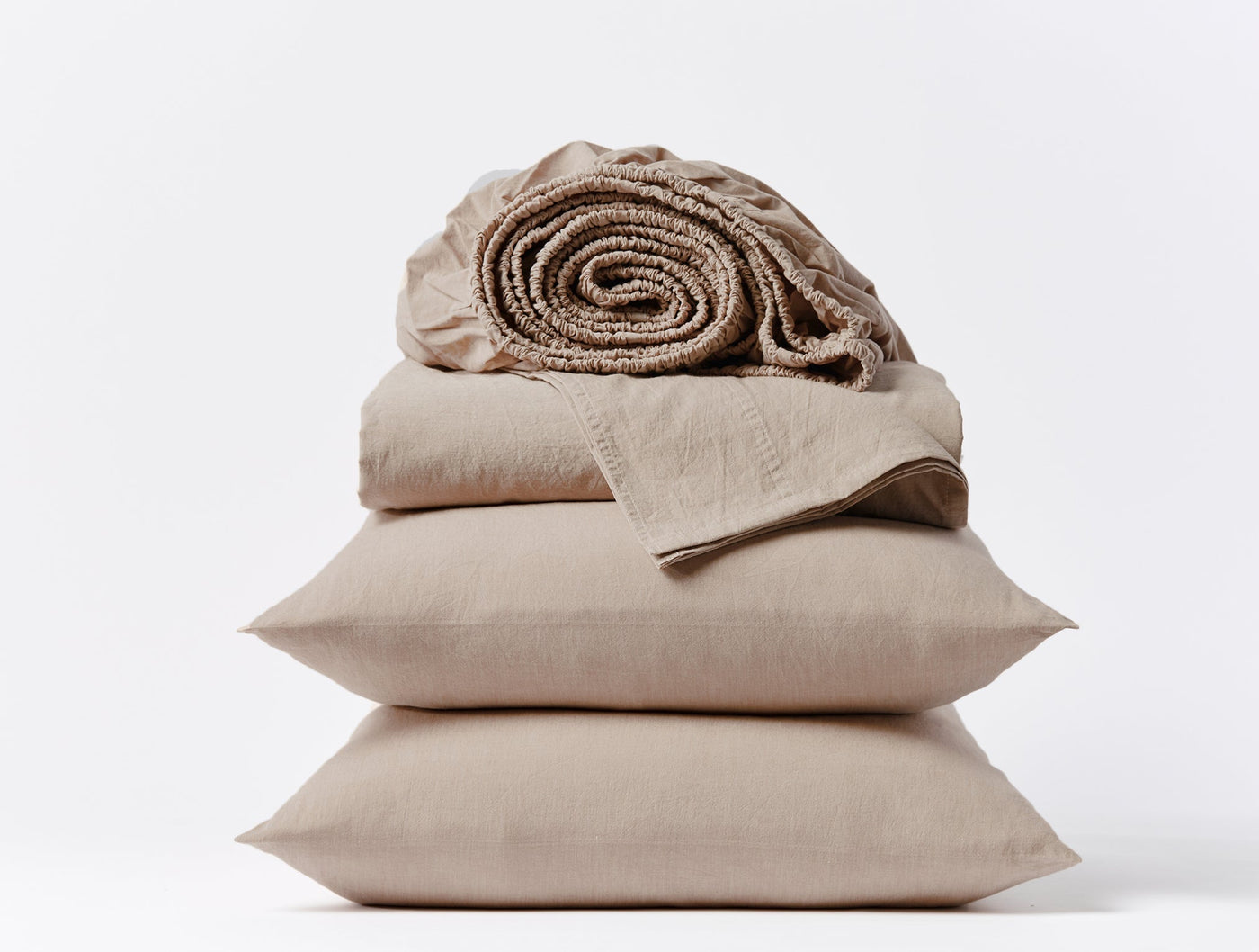 Rolled fitted sheet atop stacked flat sheet and two pillowcases in taupe crinkled percale.