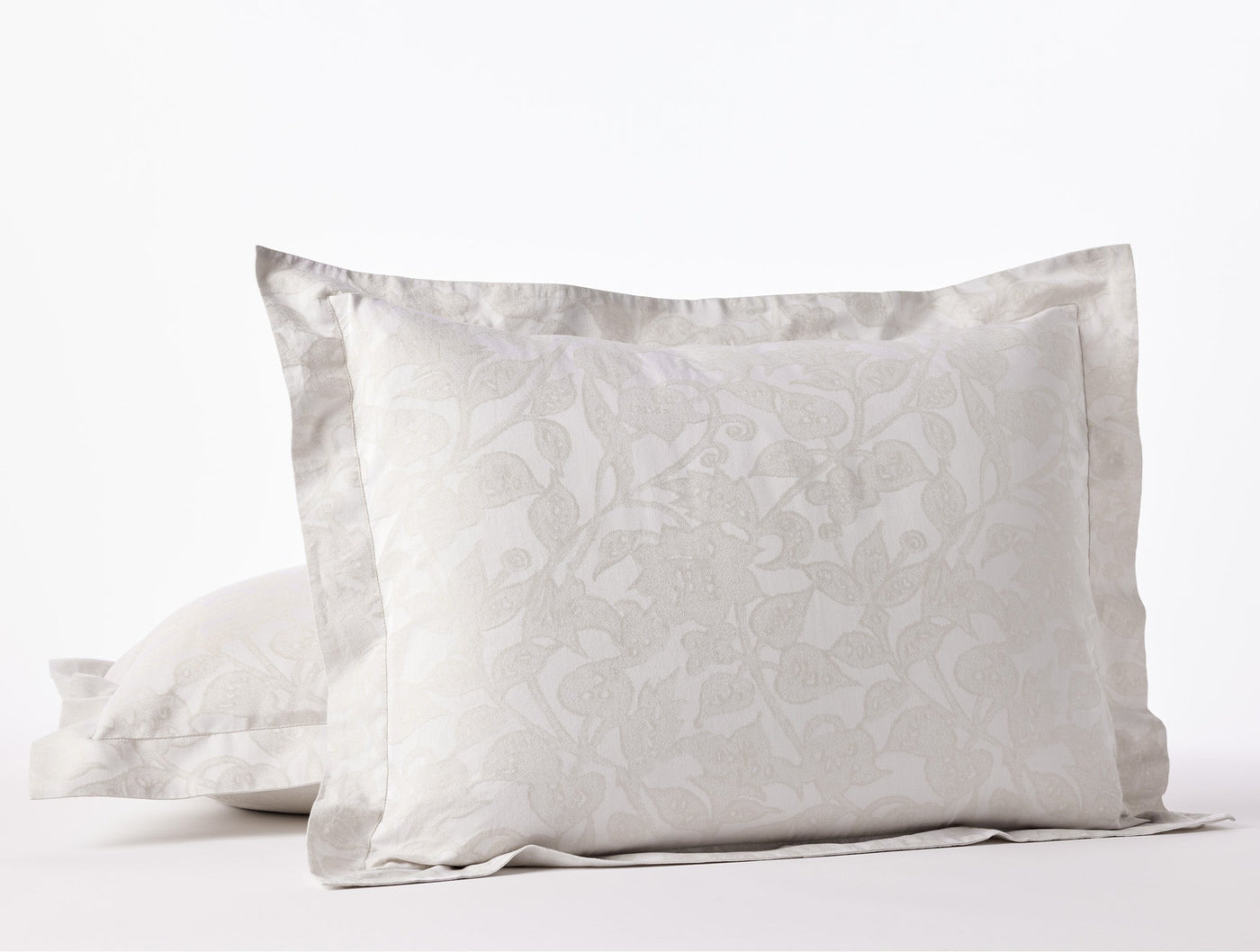 Close-up of Coyuchi Heritage Percale Jacquard shams in silver, floral woven pattern with flanged edge.