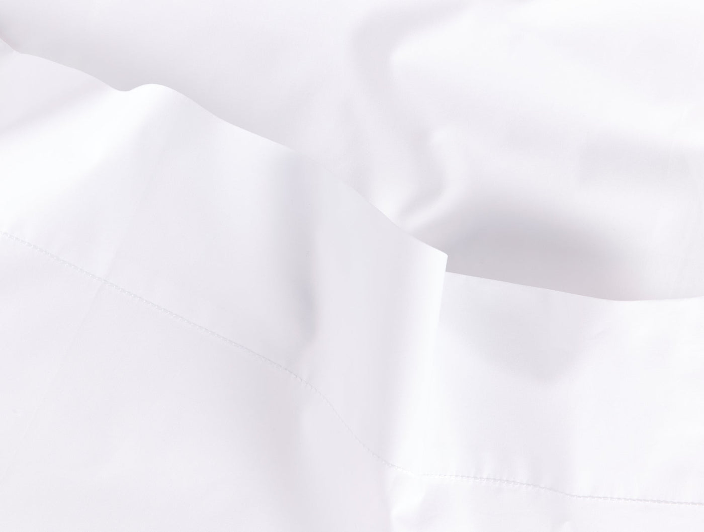 Close-up of white percale fabric with soft draping and a hemstitched border detail.