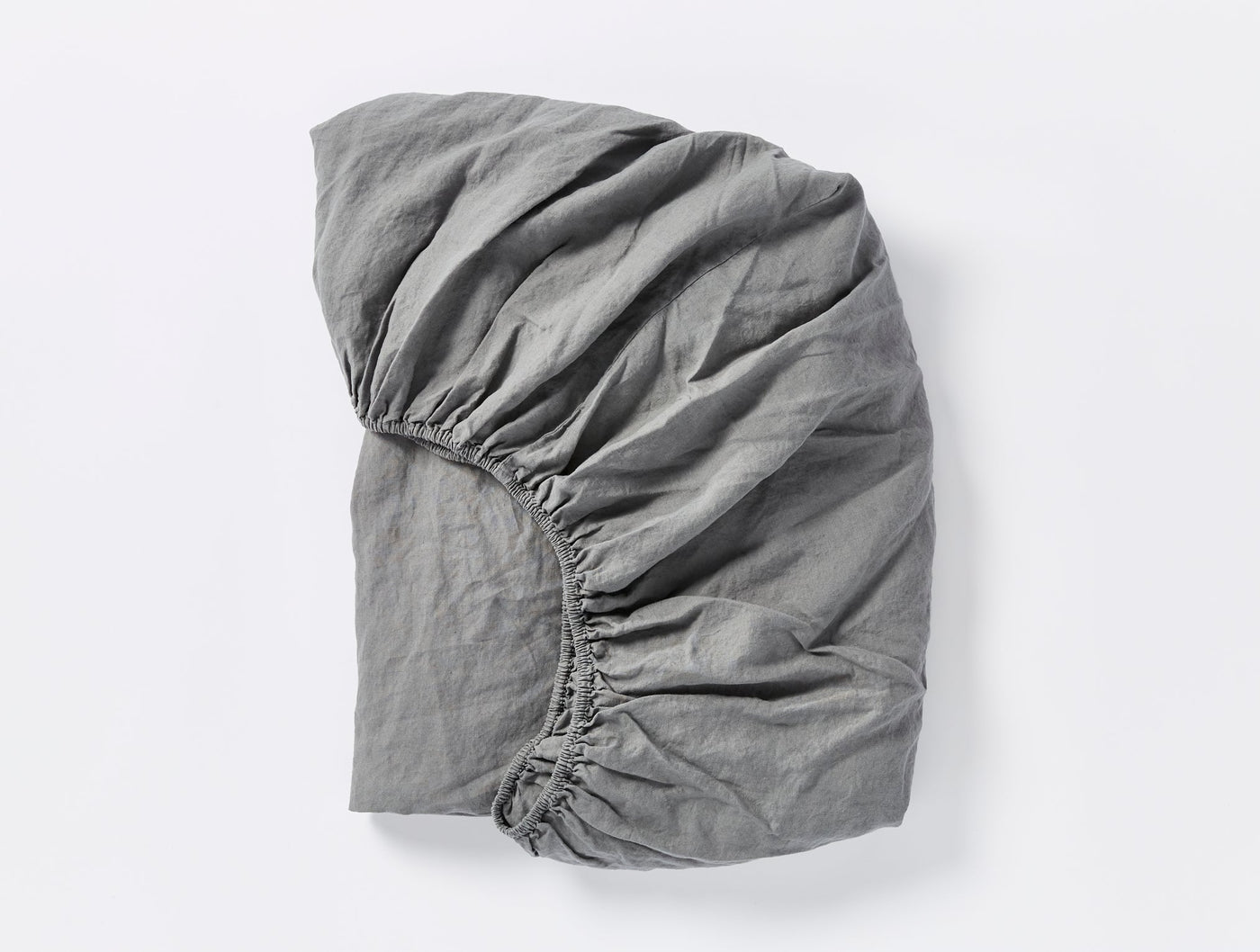 Close-up of Coyuchi Relaxed Linen fitted sheet in slate grey, folded to show elastic corners.