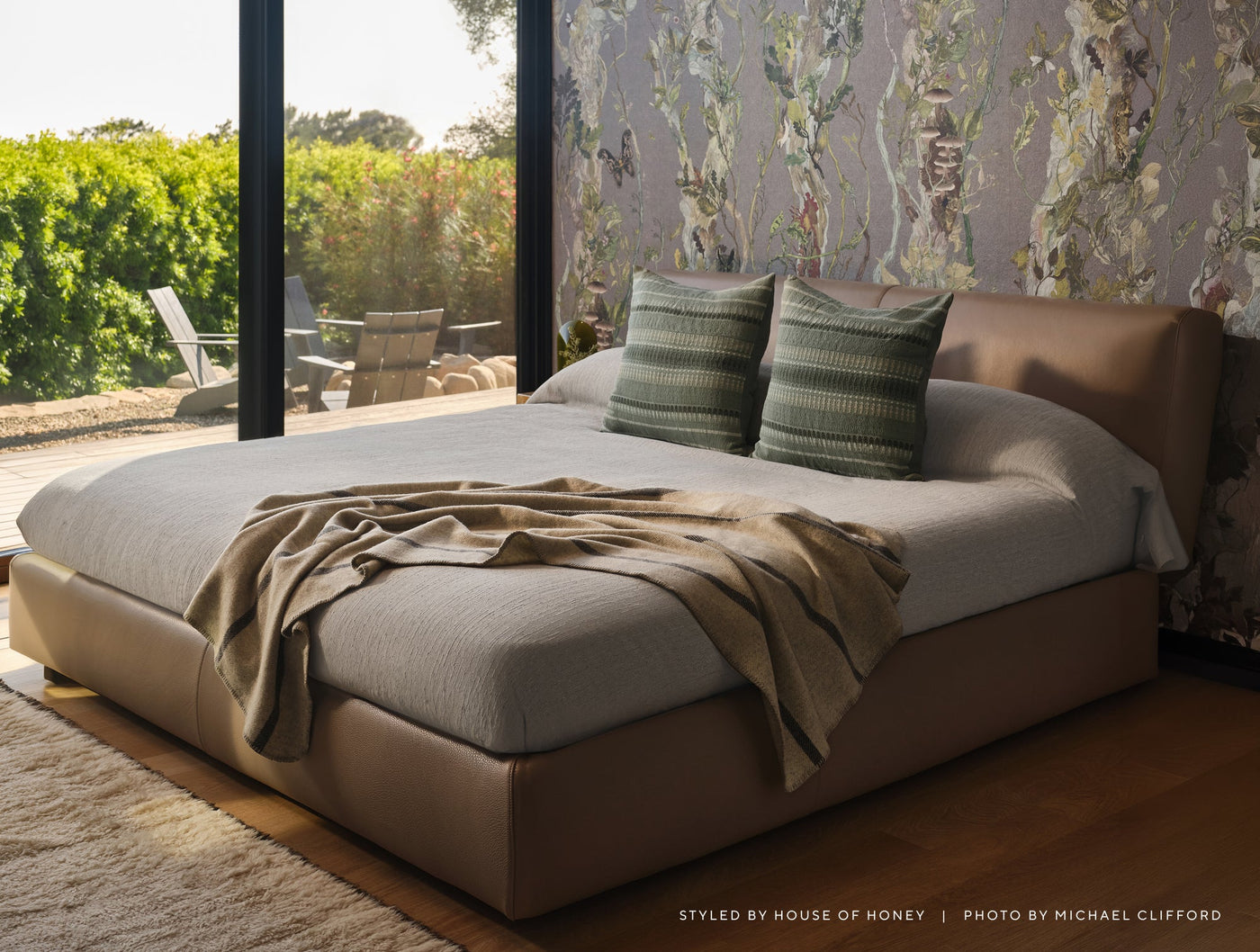 Sage green striped duvet cover on a modern bed with floral wallpaper and garden view.
