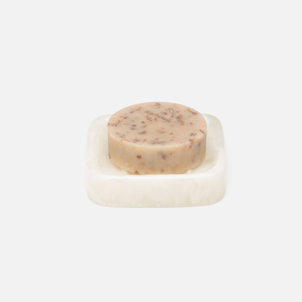 Round speckled soap bar resting on a Pigeon & Poodle Abiko white marble soap dish.