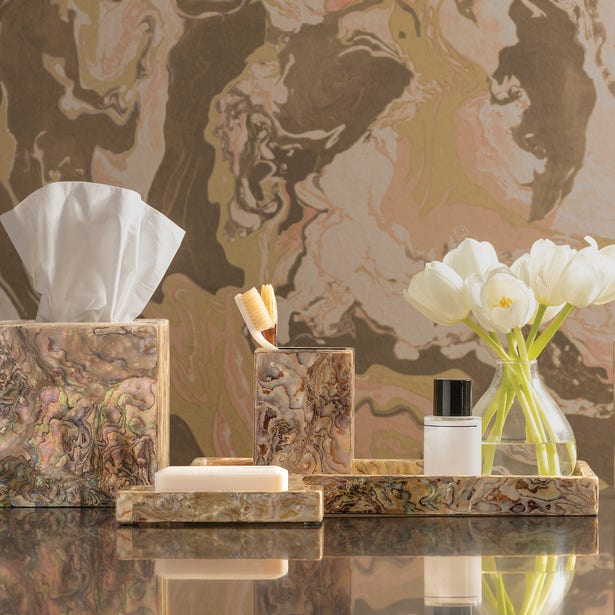 Marbled brown and gold Adana bathroom accessories set styled with white tulips on a reflective surface.