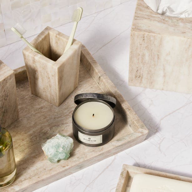 Marble bathroom tray styled with a candle, toothbrush holder, and green crystal accent.